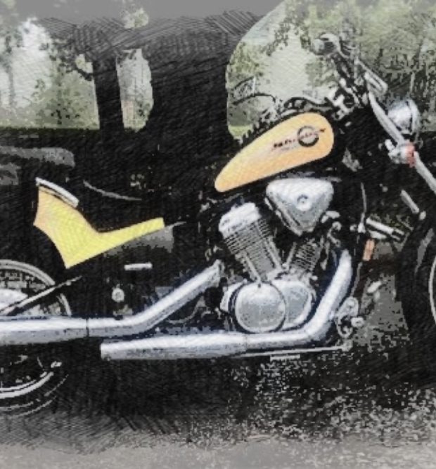 A vintage motorcycle with a yellow and black design parked on a wet surface.